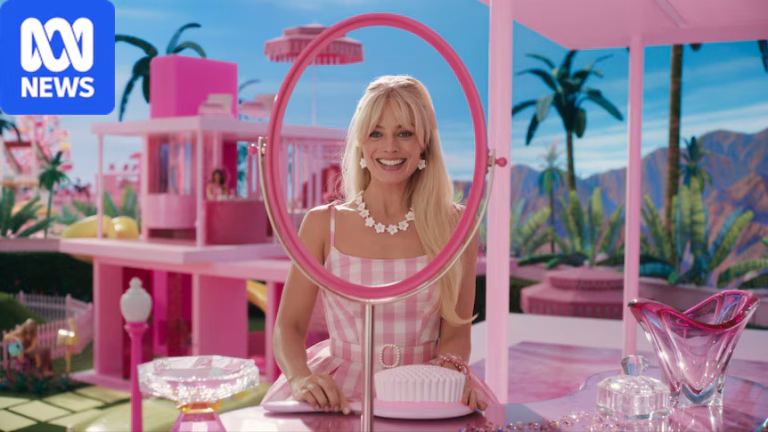 The actor Margot Robbie in a pink dress and long blonde hair playing the character Barbie, standing in a pink set